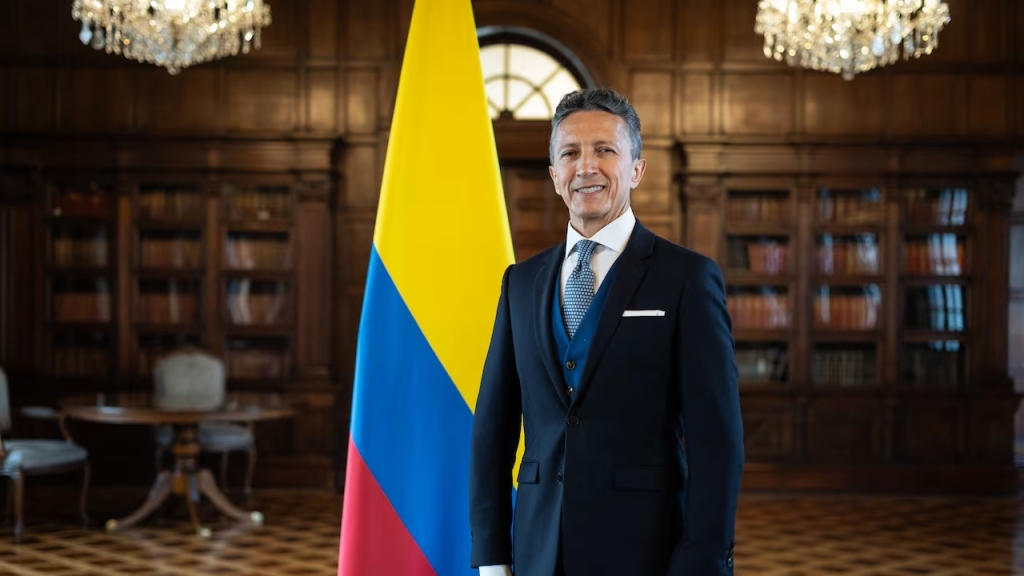 Foto del Embajador Javier Darío Higuera al lado de la bandera de Colombia